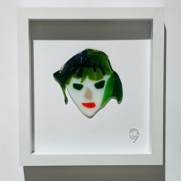 abstract female face with green hair and red lipstick in glass picture frame